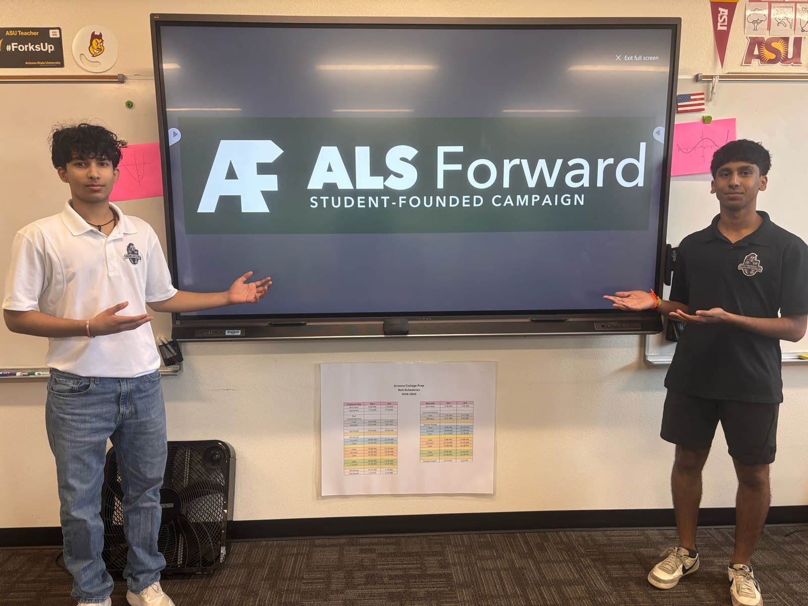 Two ALS Forward students on either side of a classroom screen showing the ALS Forward logo
